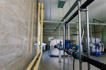 Person installing flooring, holding a plank covered with adhesive. Tools and bucket nearby.