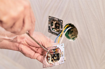 Man using a bow saw to cut wood in a workshop with tools and wood shavings.