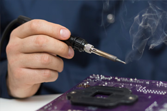 Person installing flooring, holding a plank covered with adhesive. Tools and bucket nearby.