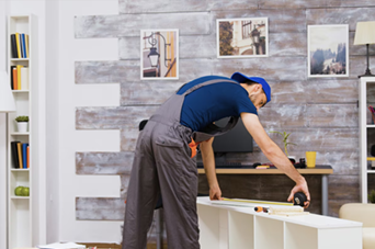 Hands testing wires with a multimeter on a white terminal block on a wooden surface.