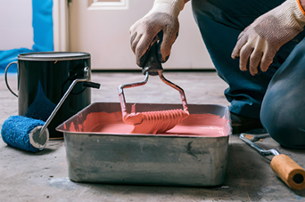 Man sawing wood in a workshop, wearing an apron, with wood scraps and tools.