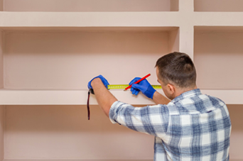 Hands testing wires with a multimeter on a white terminal block on a wooden surface.