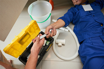 Man using a bow saw to cut wood in a workshop with tools and wood shavings.