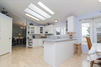 Person installing flooring, holding a plank covered with adhesive. Tools and bucket nearby.