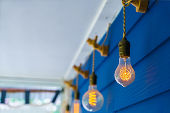Man sawing wood in a workshop, wearing an apron, with wood scraps and tools.