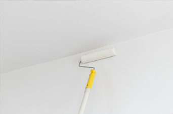 Person installing flooring, holding a plank covered with adhesive. Tools and bucket nearby.