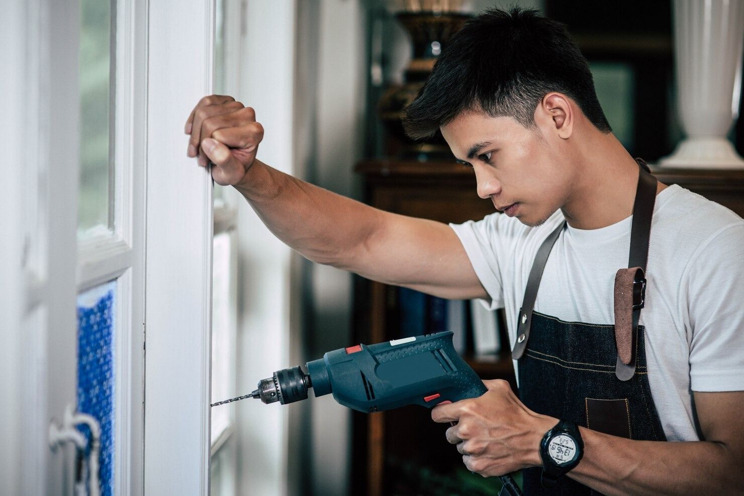 Man using a bow saw to cut wood in a workshop with tools and wood shavings.