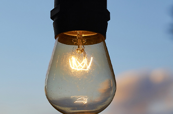 Lit lightbulb against a blue sky.