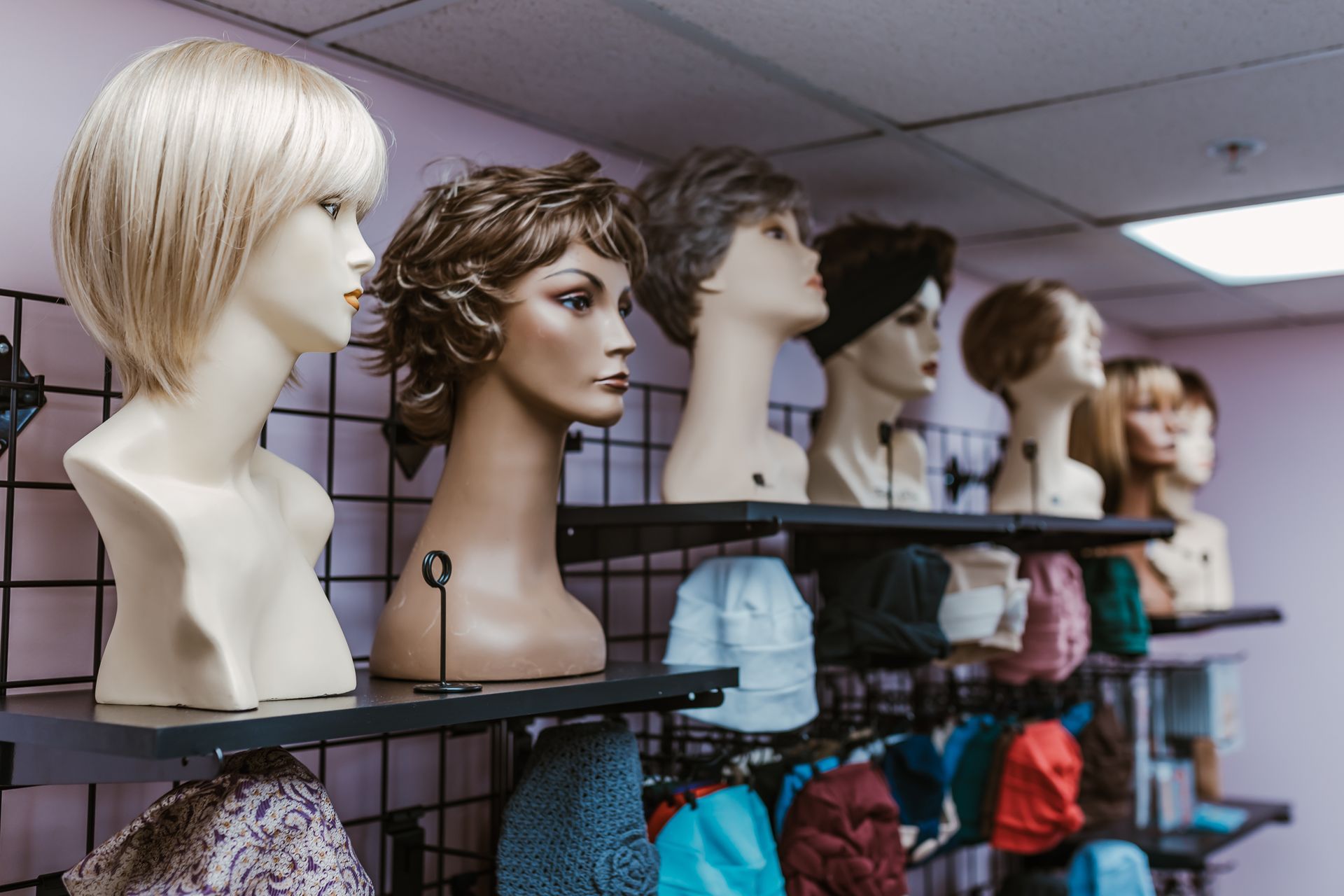 A row of mannequin heads with wigs on display in a store.