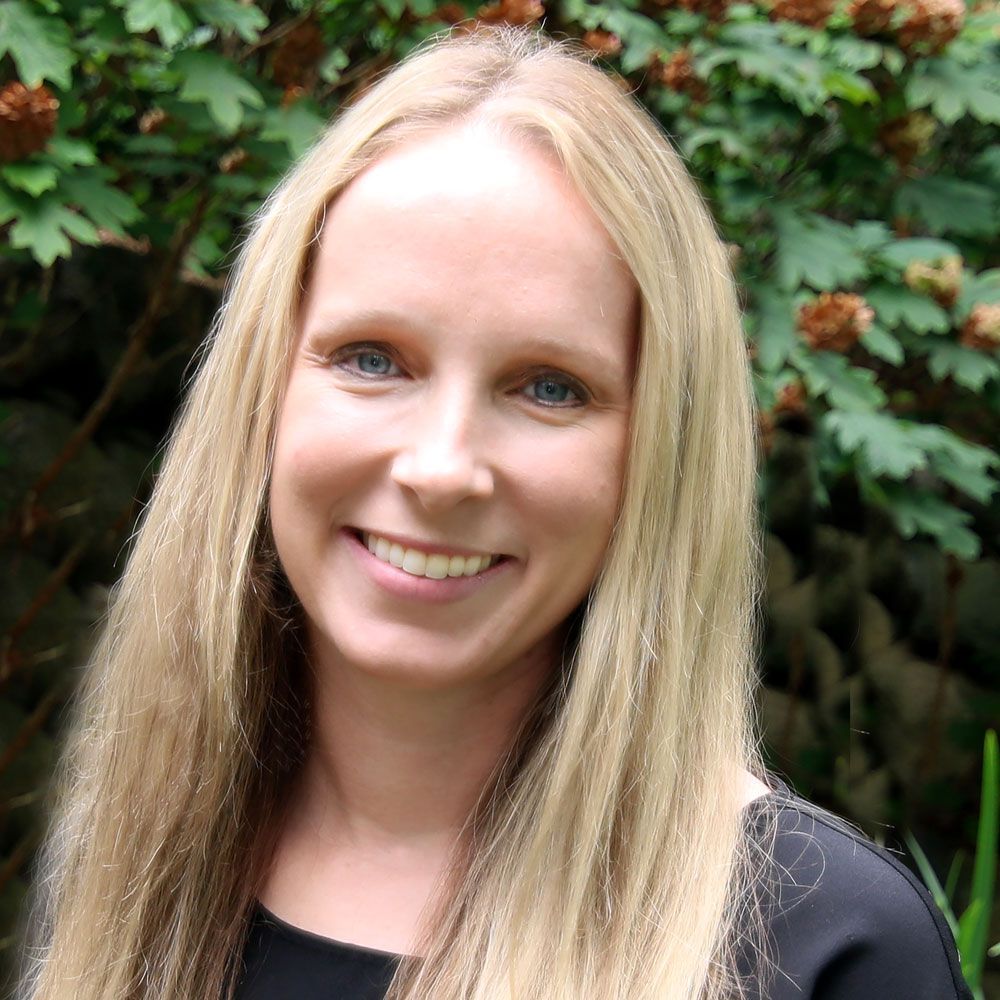 A woman with long blonde hair is smiling for the camera