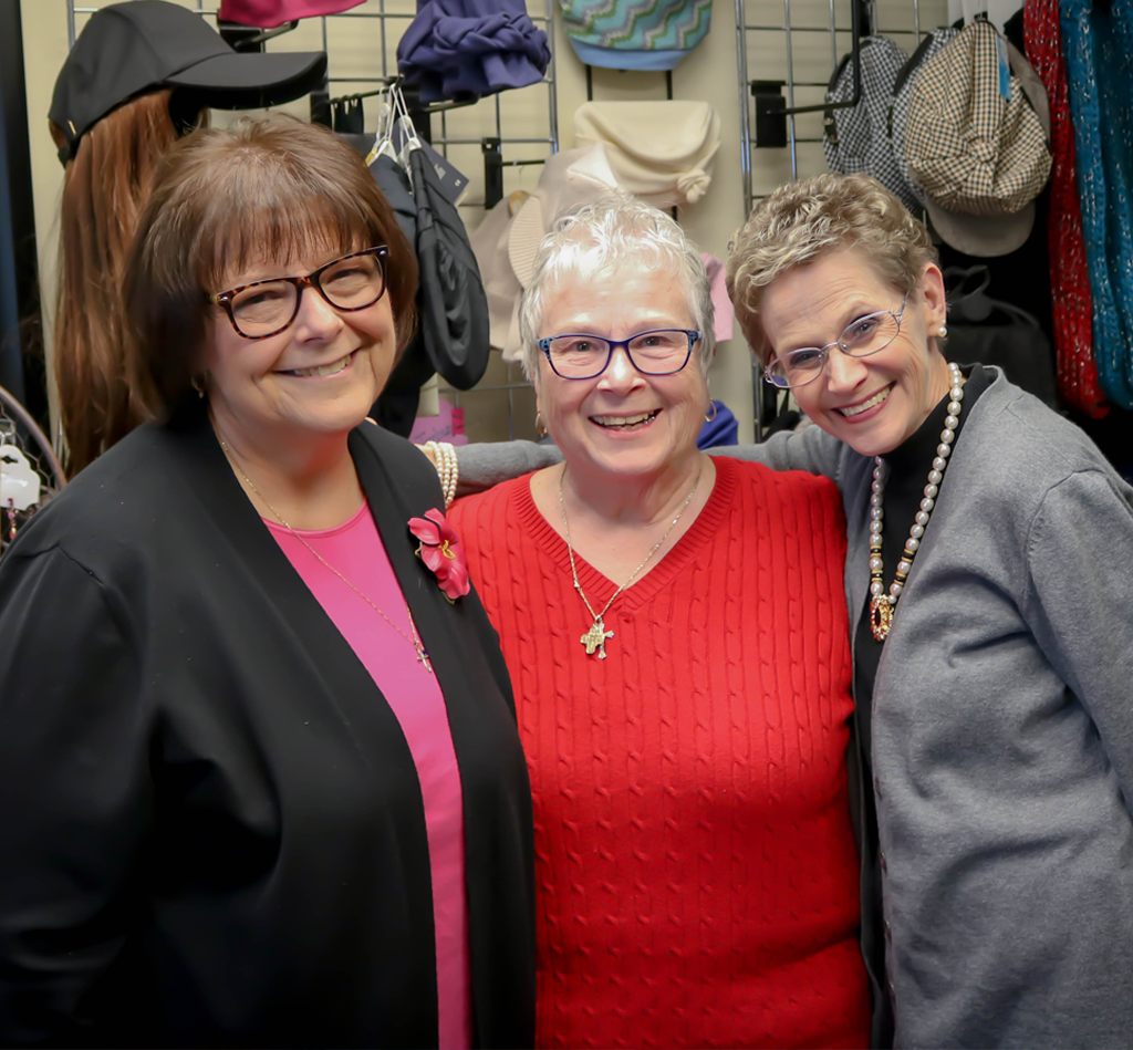 Three women are posing for a picture in a clothing store