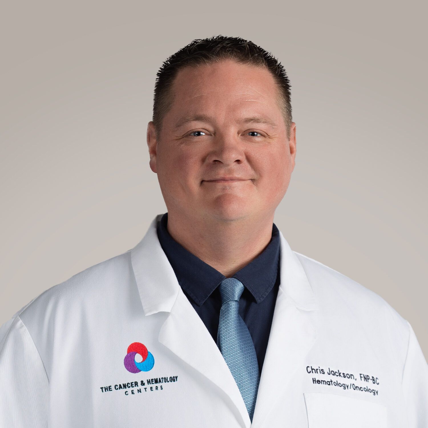 A man wearing a white lab coat and a blue tie