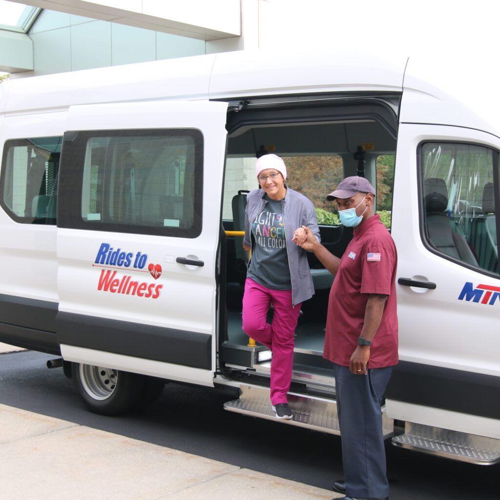 Two people are getting out of a van that says rides to wellness