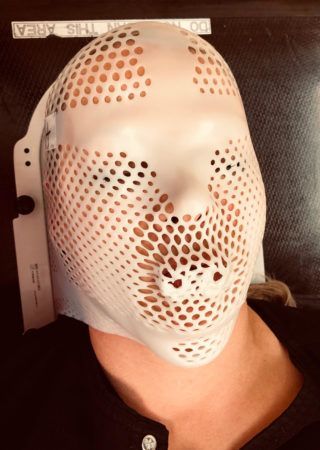 A person wearing a white mask with holes in it