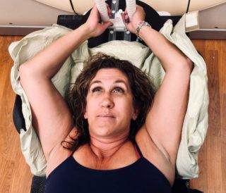 A woman is laying on a bed with her arms outstretched