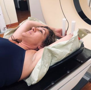 A woman in a blue tank top is laying in a hospital bed