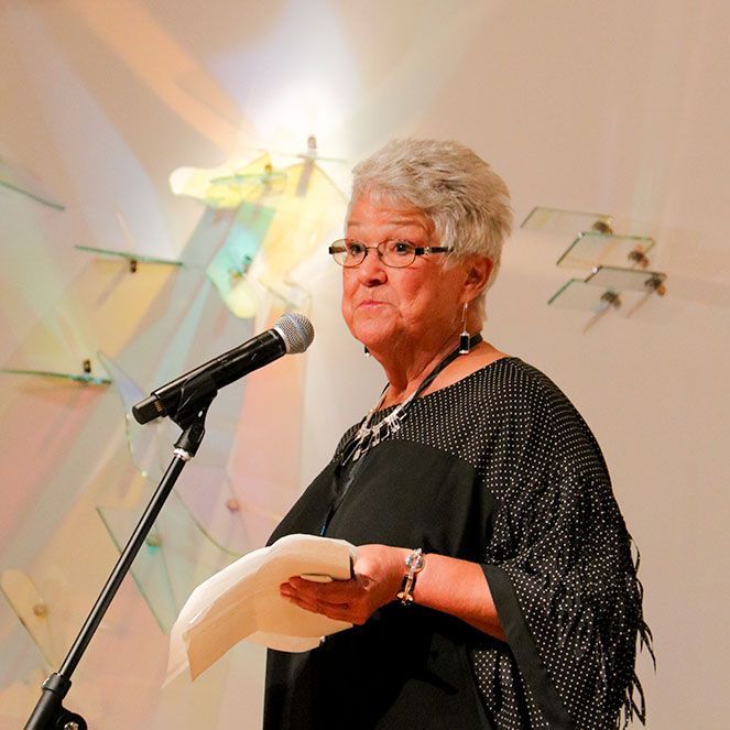 A woman is speaking into a microphone while holding a piece of paper