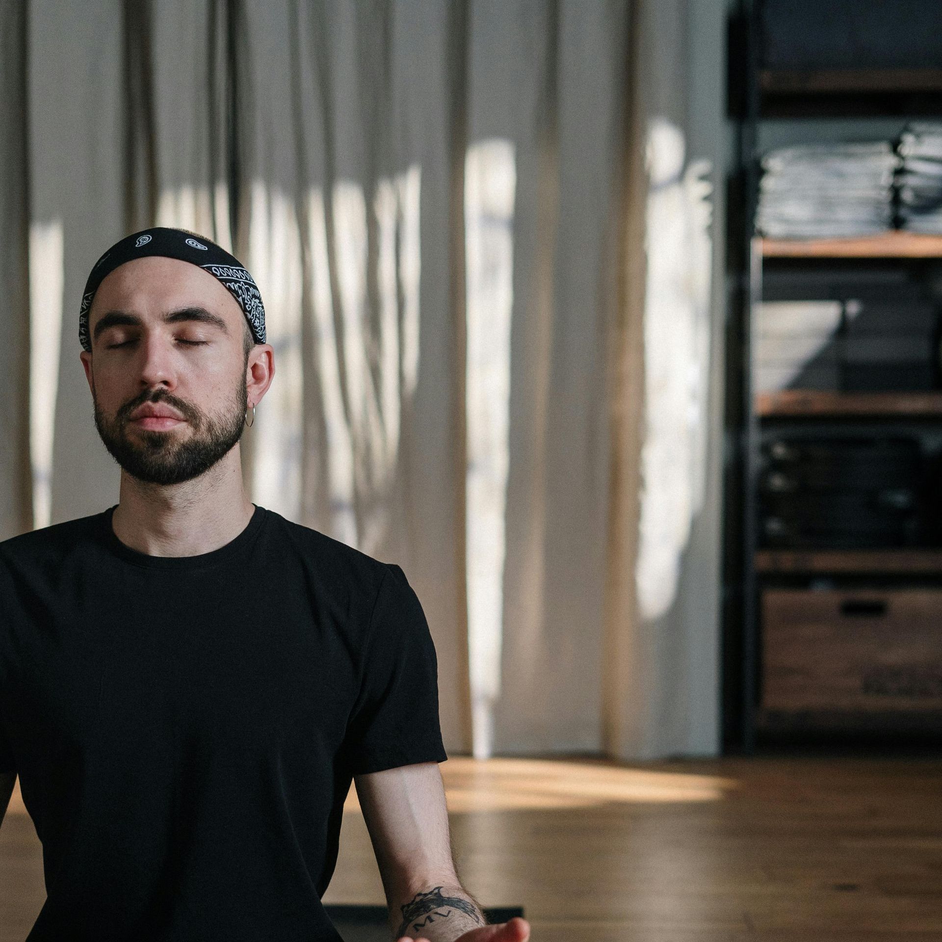 A person is sitting on a yoga mat in front of a laptop computer.