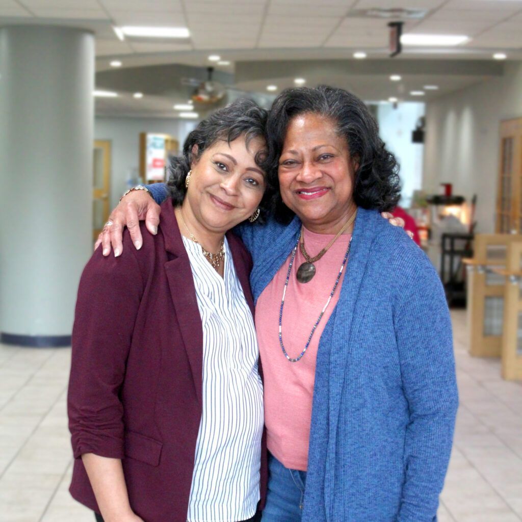 Two women are posing for a picture together in a hallway