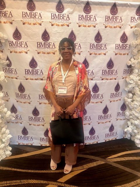 Shekita Long standing in front of the BMBFA (Black Mothers Breastfeeding Association) Back drop at the Motown Experience Breastfeeding Conference