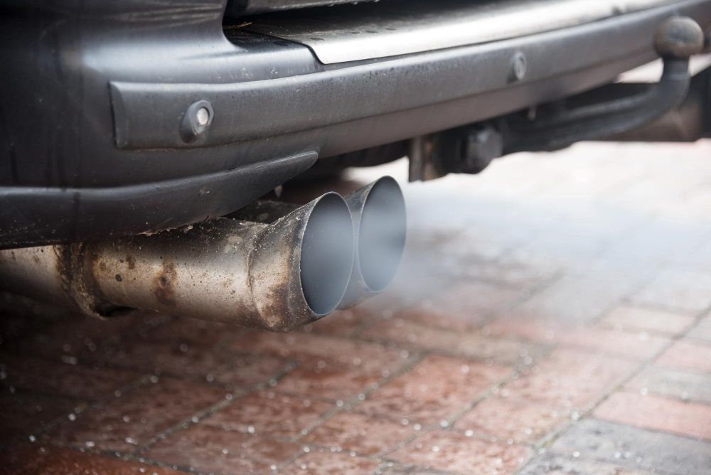 Exhaust pipes emitting gray smoke from the rear of a vehicle.