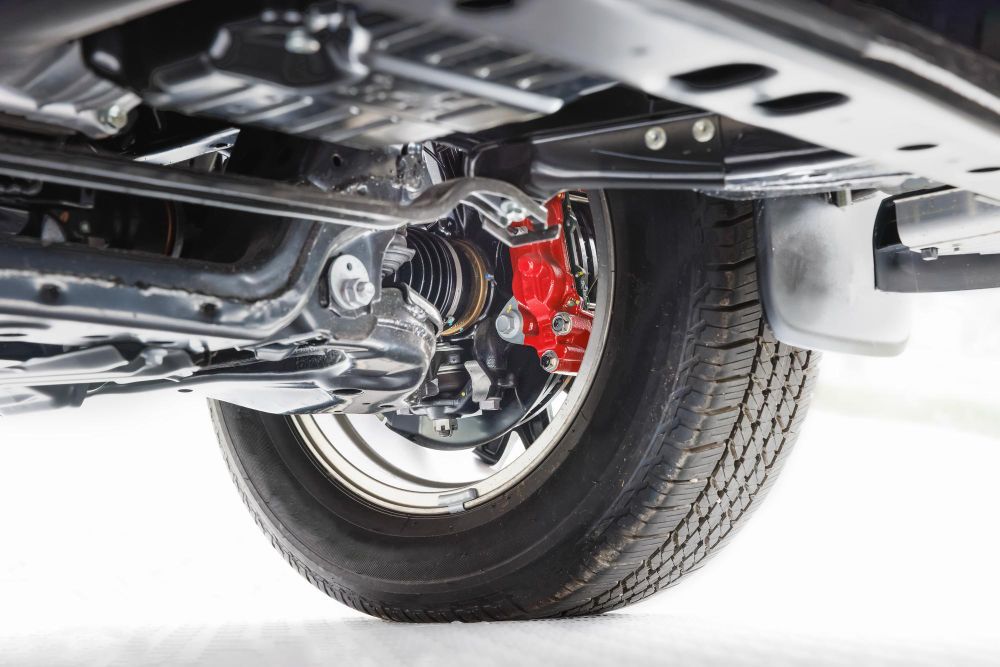 Undercarriage view of a vehicle: a tire, red brake caliper, and suspension components.