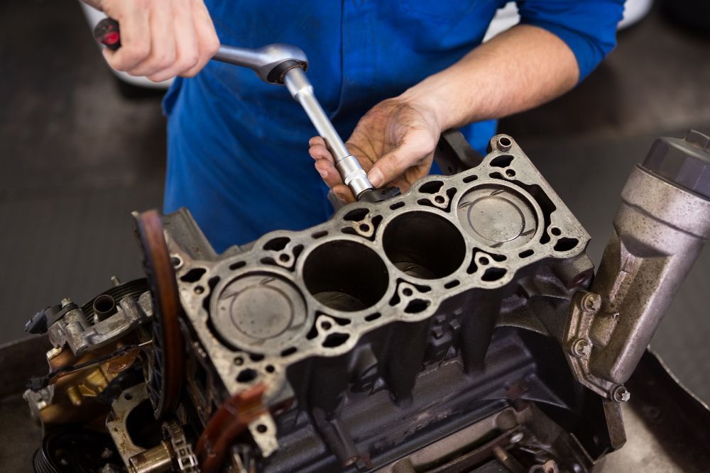 Mechanic using a wrench to work on a car engine in a garage.
