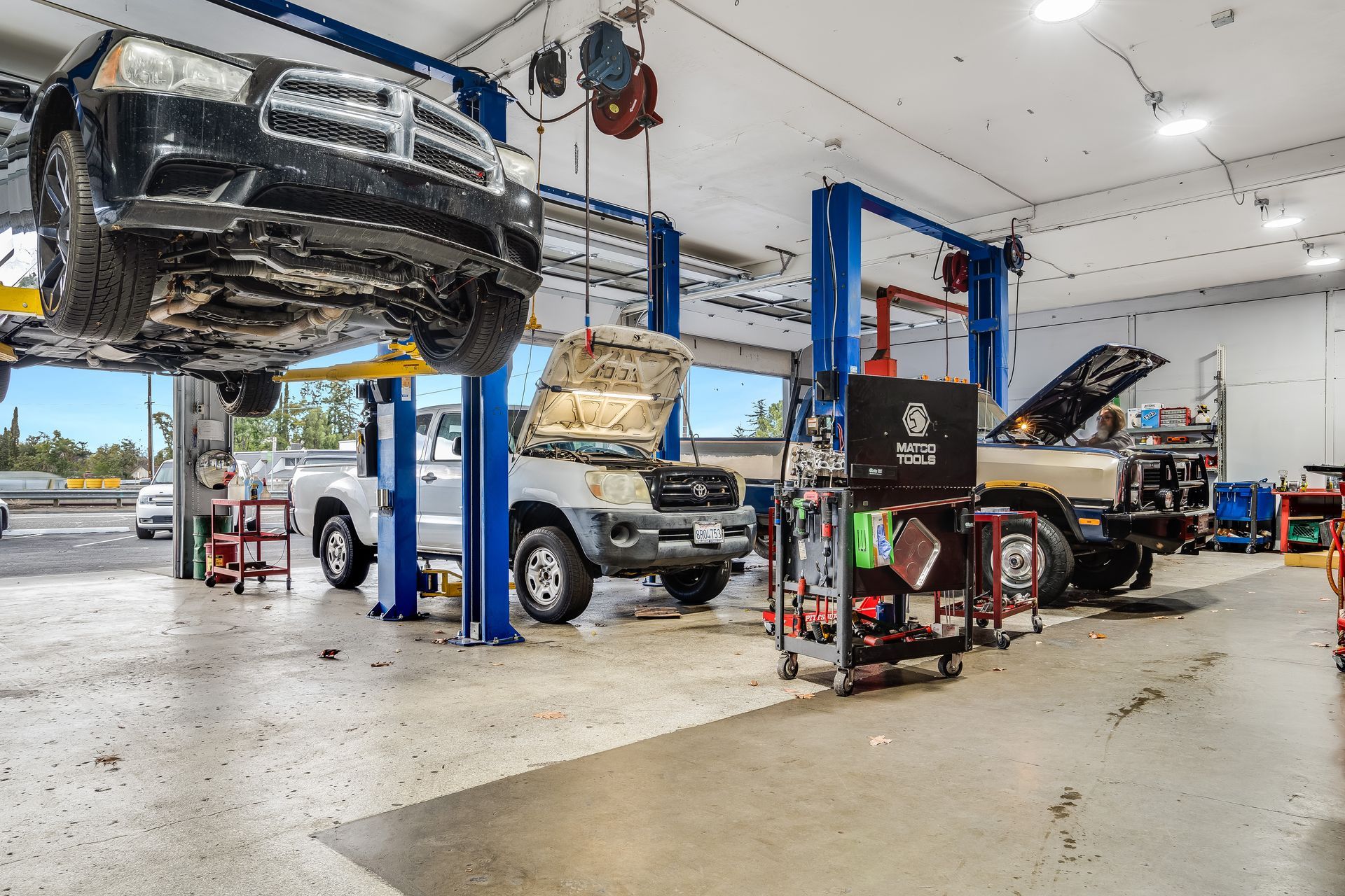 Cars being worked on in a garage with lifts, tools, and a white interior.