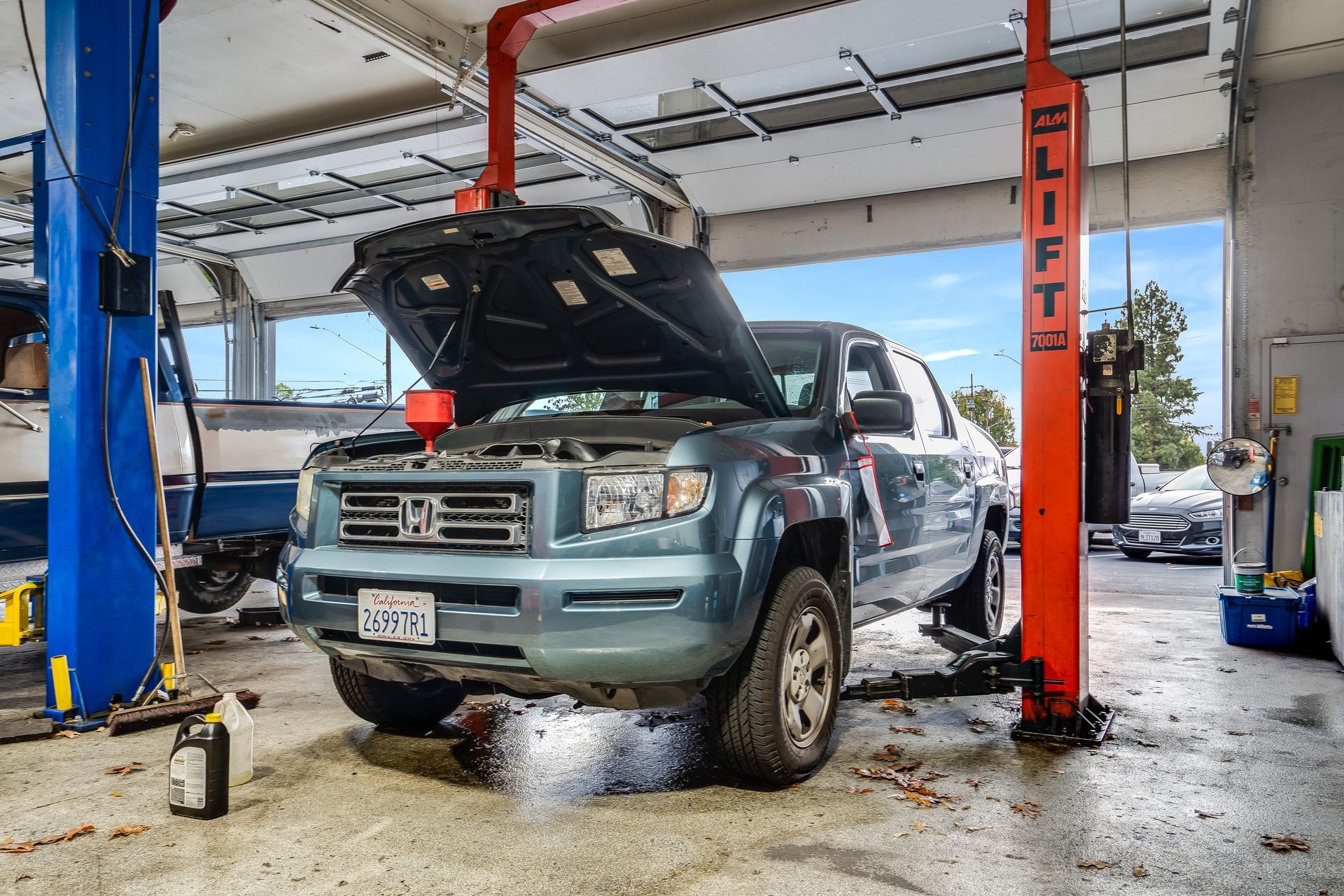 A truck on a lift with its hood open, likely undergoing maintenance in a garage.
