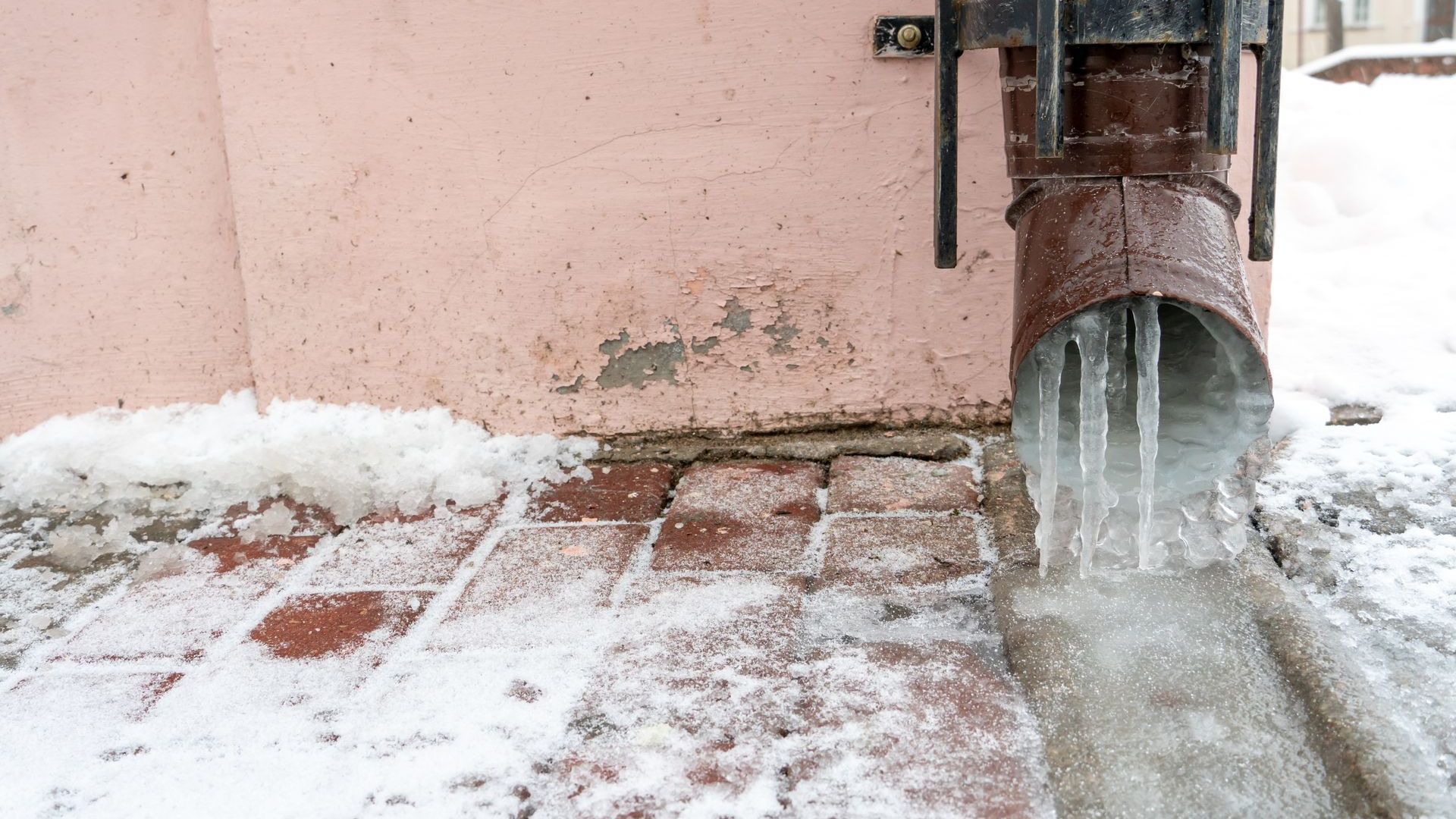 A pipe with icicles coming out of it is covered in snow.
