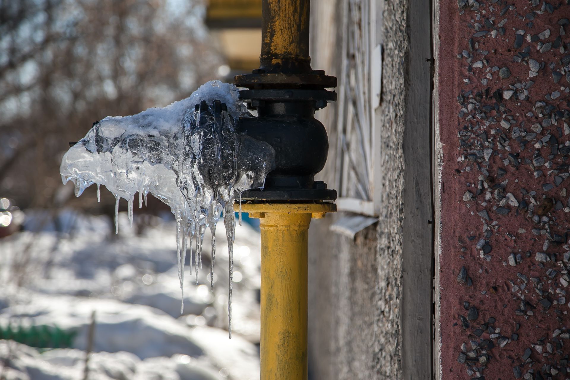 A pipe with icicles coming out of it is covered in snow.
