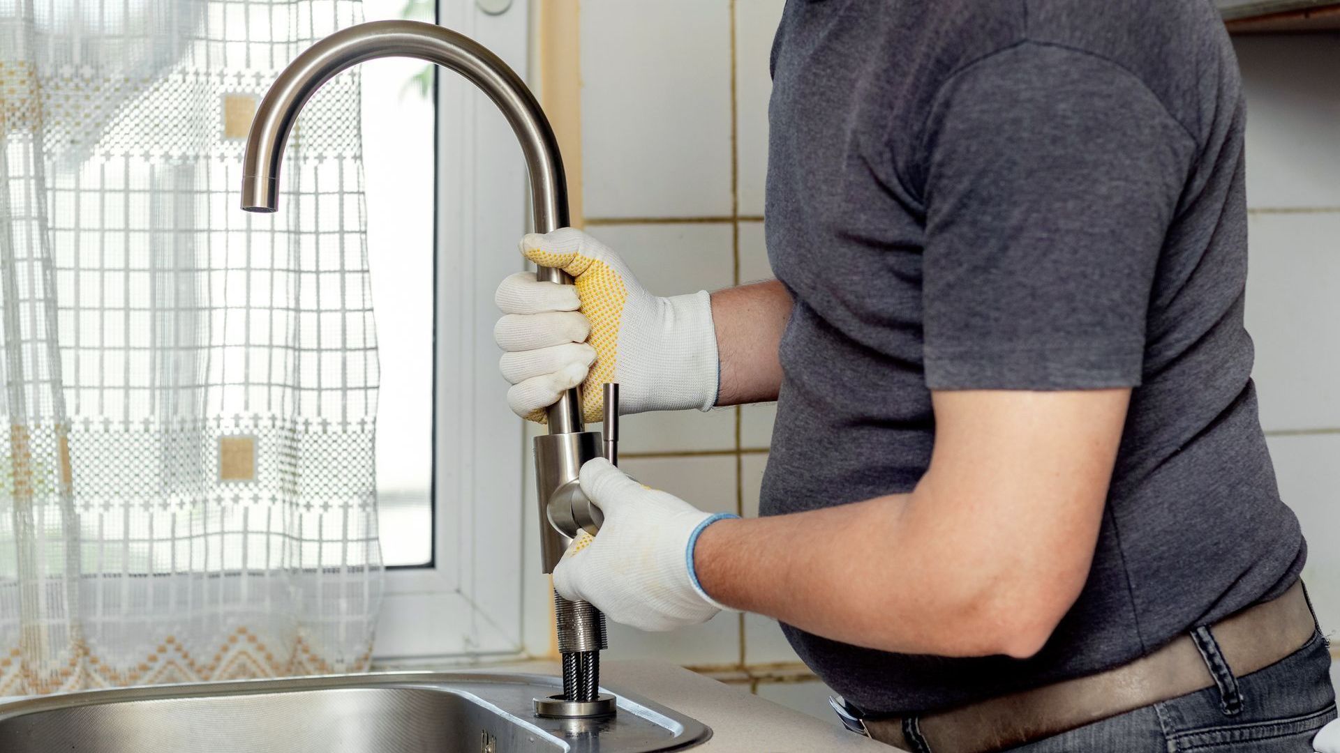 A man is fixing a faucet in a kitchen.