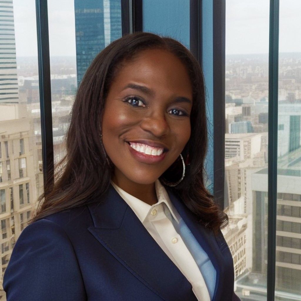 Smiling professional in navy blazer standing by large office windows with city view