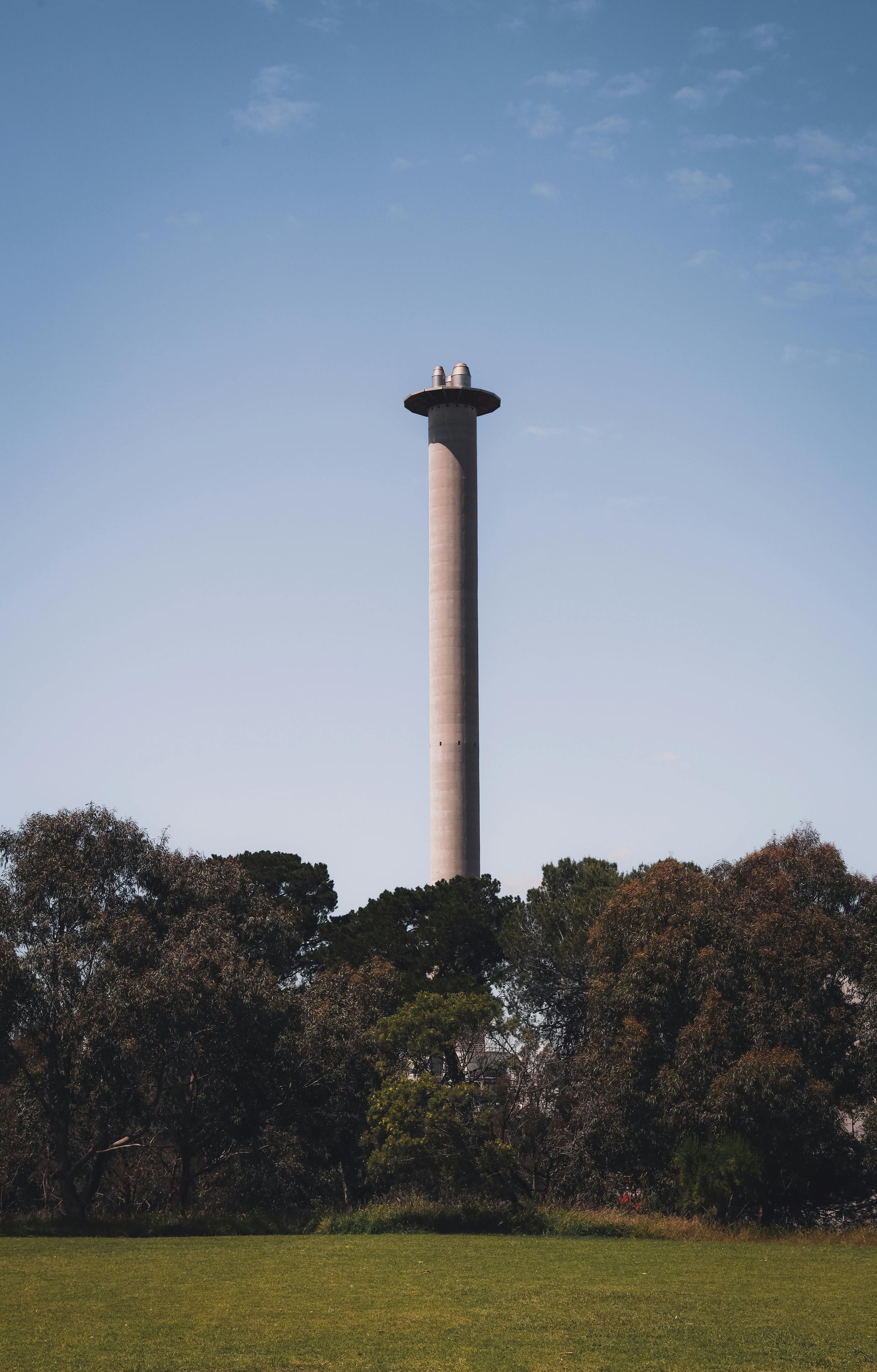 A tall concrete tower is sitting in the middle of a grassy field.
