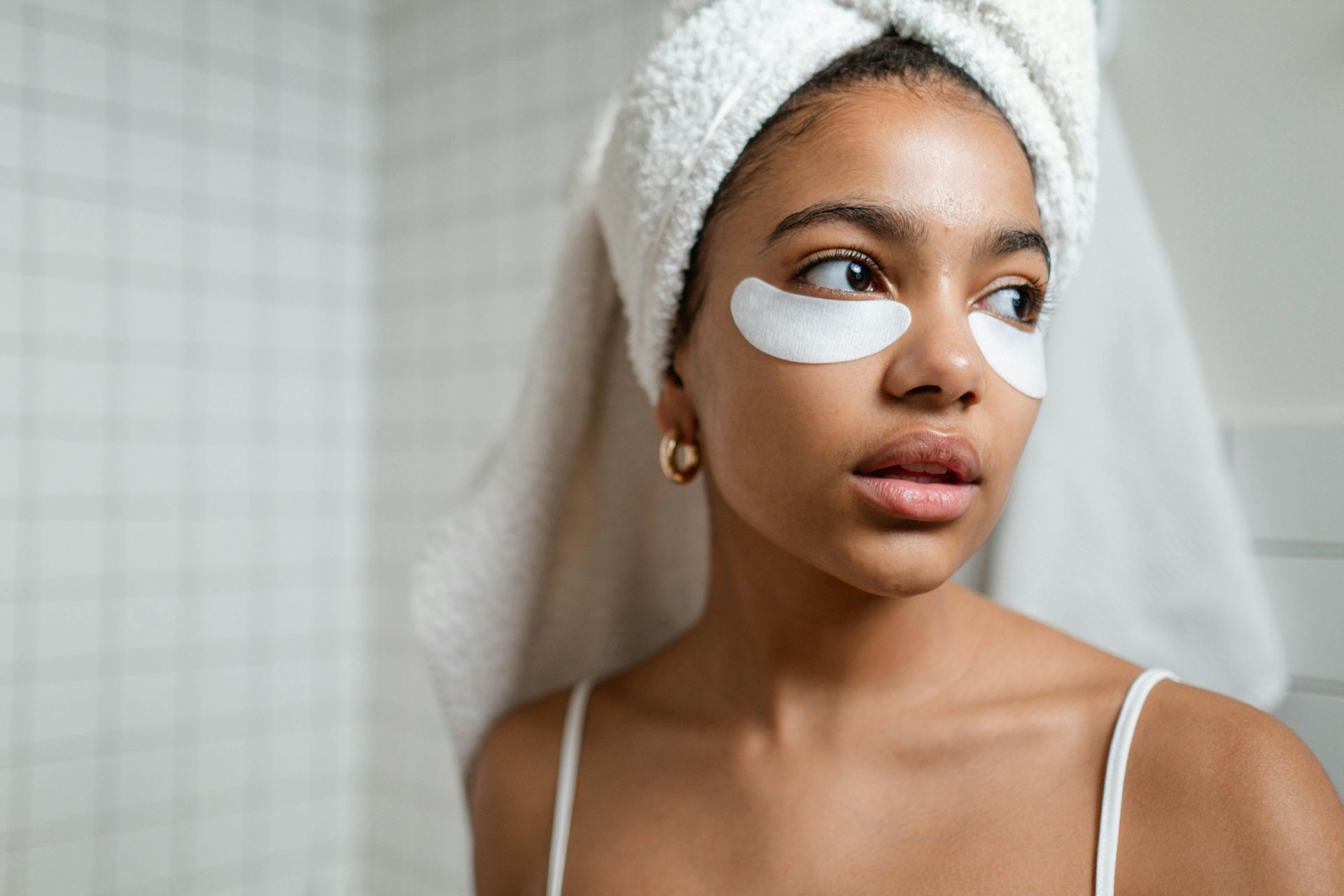 A woman with a towel wrapped around her head and eye patches on her eyes.