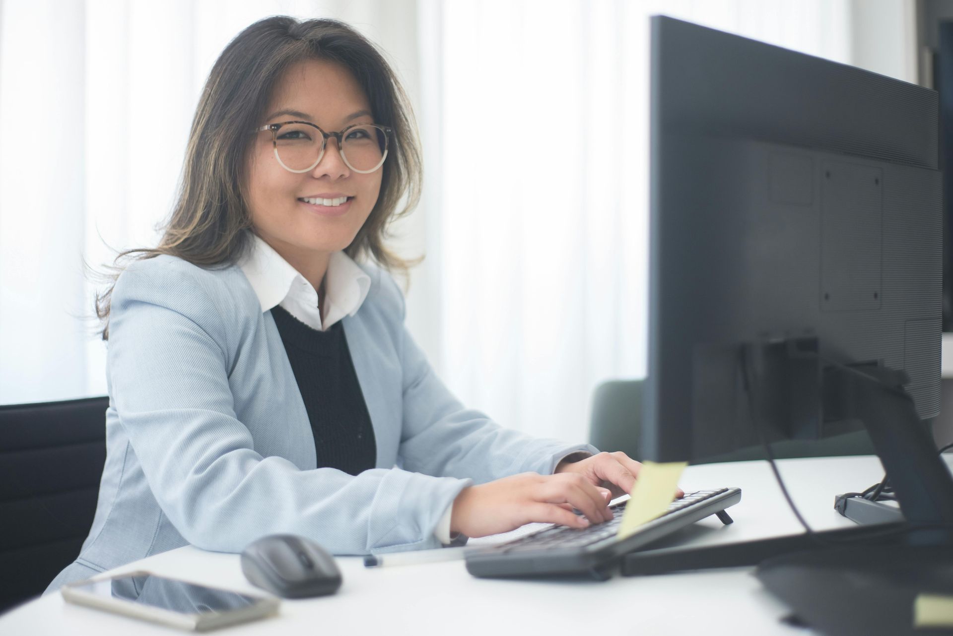 A woman is sitting at a desk in front of a computer.