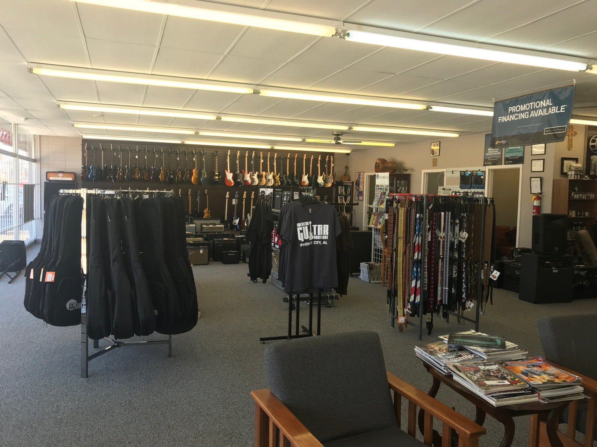 Music store interior with guitars on display, cases, shirts, and accessories.
