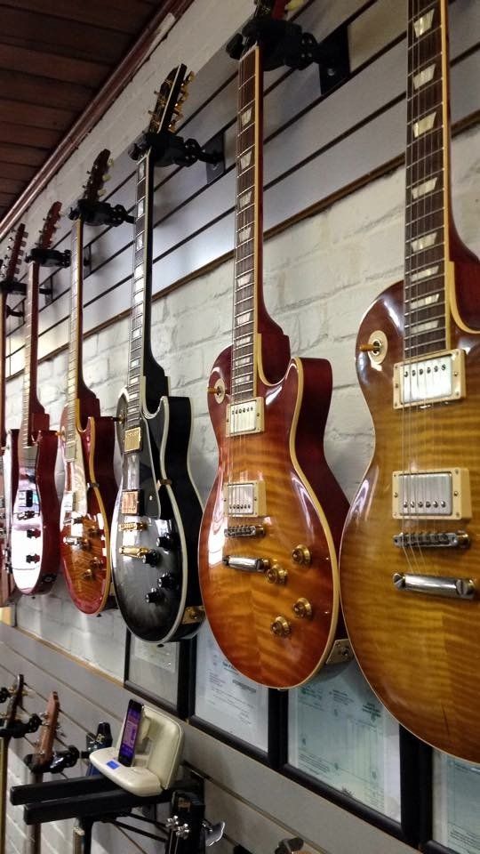 Collection of electric guitars mounted on a wall; various wood finishes.