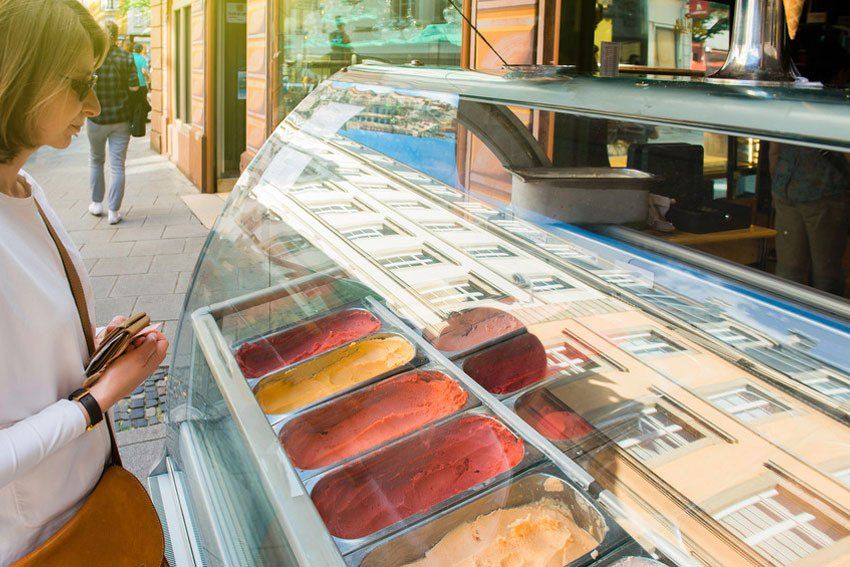 Woman buying traditional French ice cream on the market stall at the French patisserie gourmet cafe