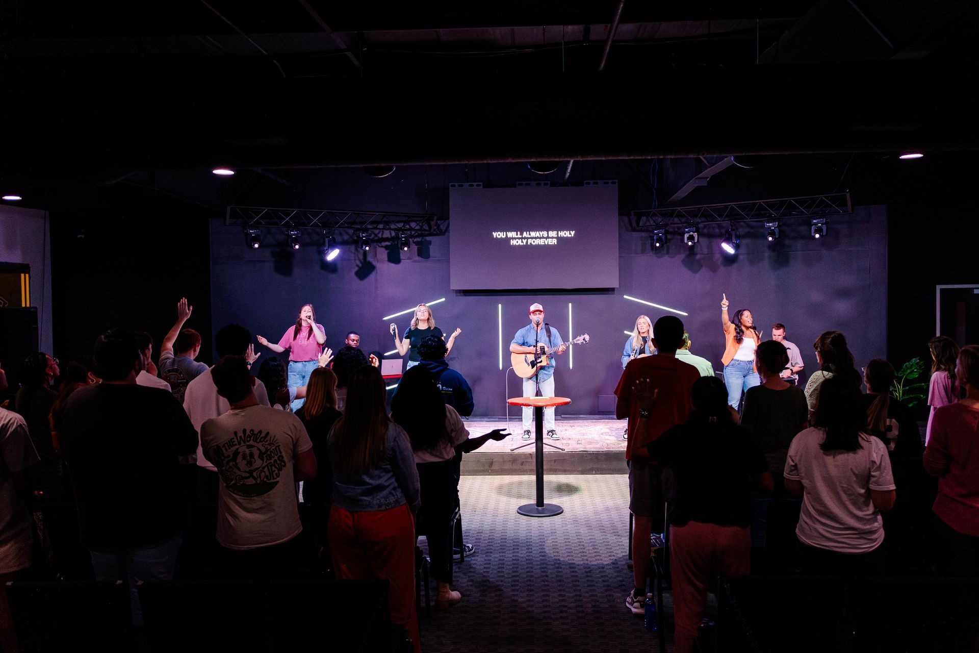 A group of people are standing on a stage singing into microphones.