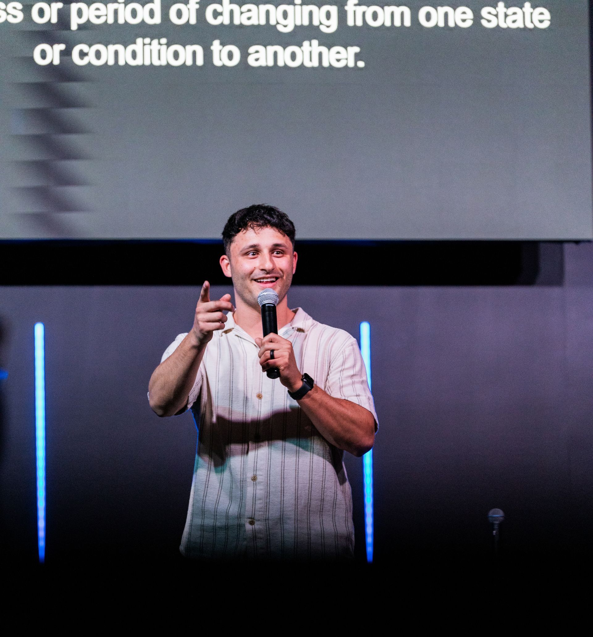 A man holding a microphone in front of a screen that says 