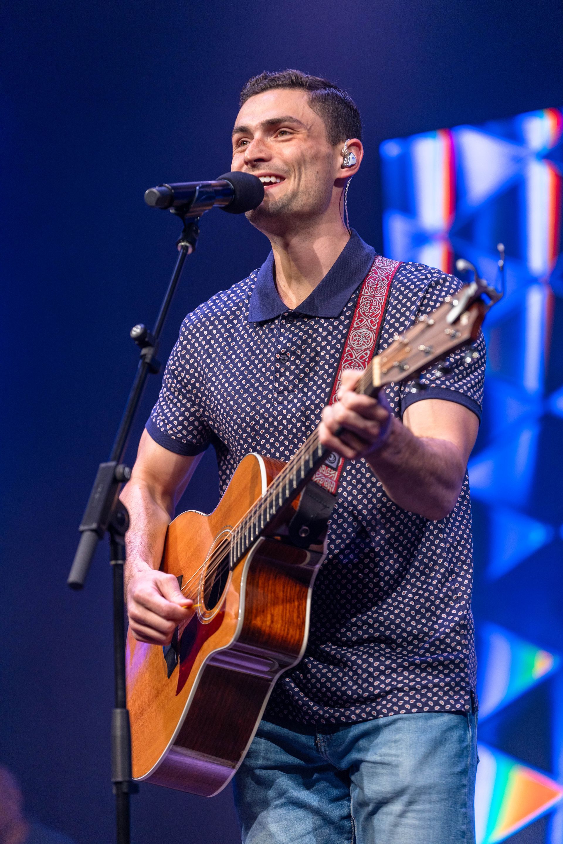 A man is playing a guitar and singing into a microphone on a stage.