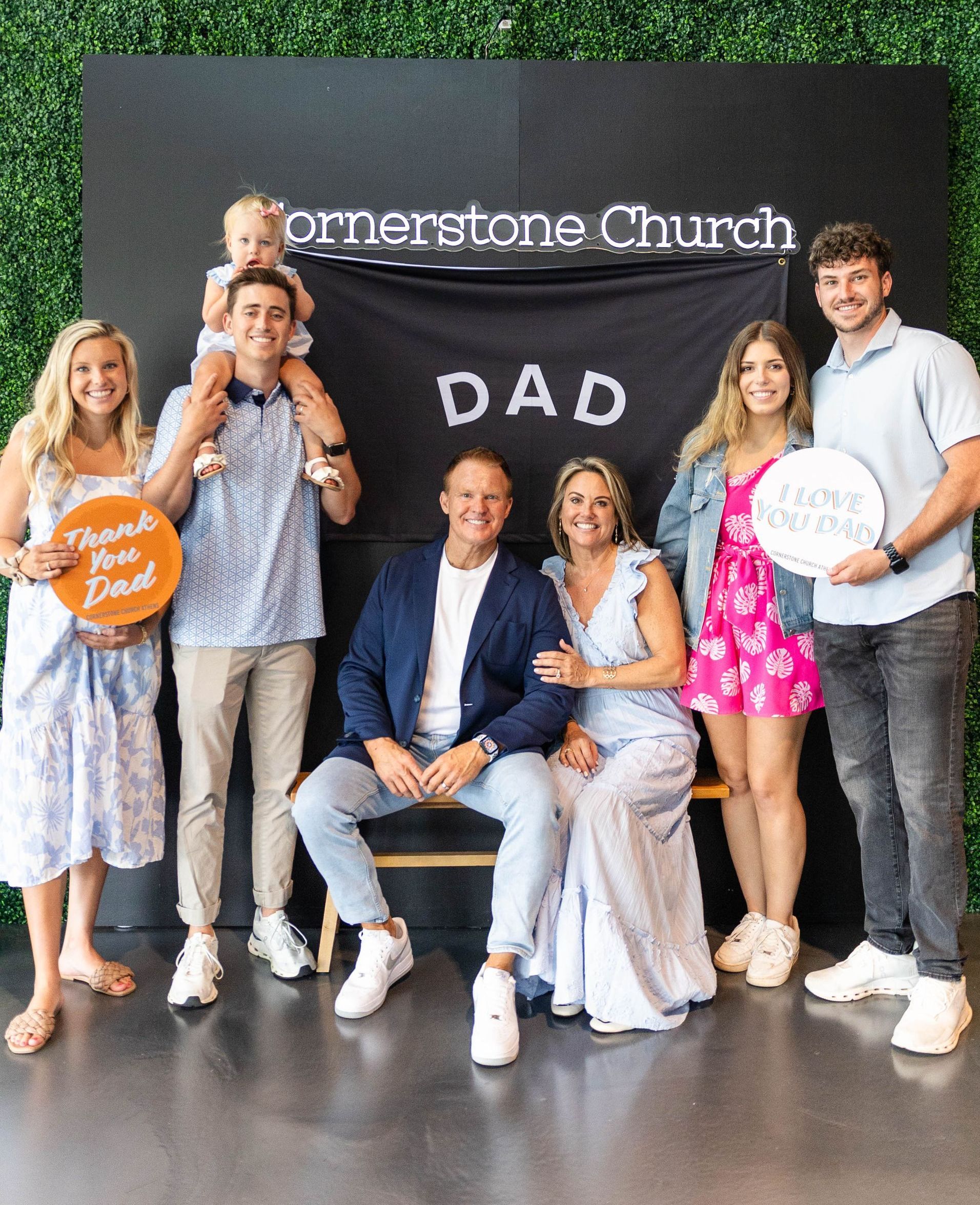 A group of people are posing for a picture in front of a sign that says dad.