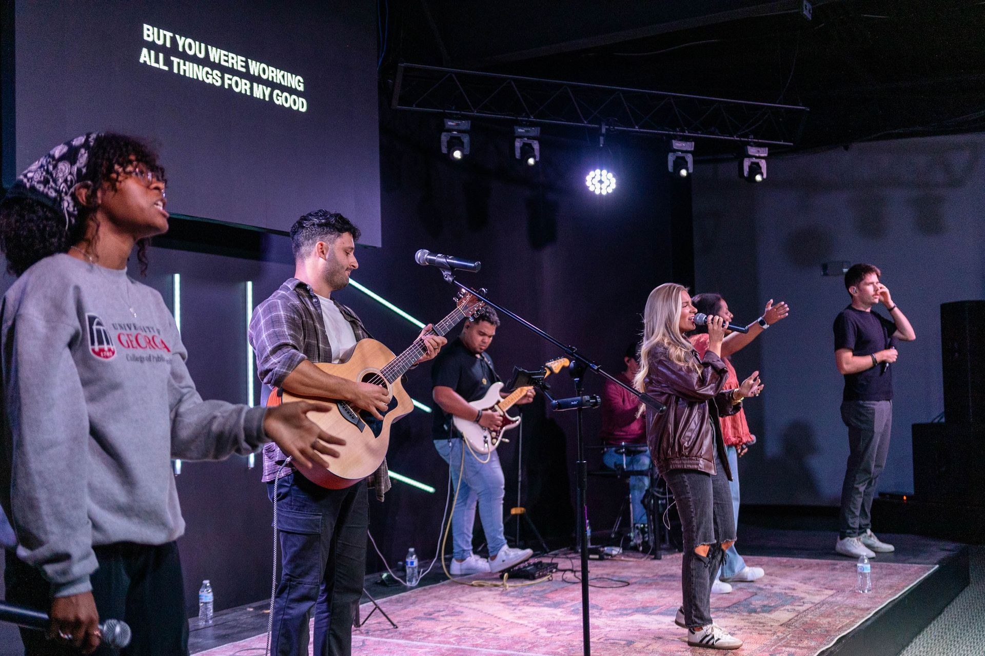 A group of people are standing in a room talking to each other.