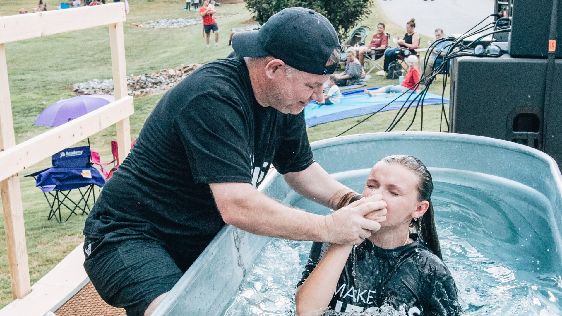 A man is baptizing a young girl in a tub of water.