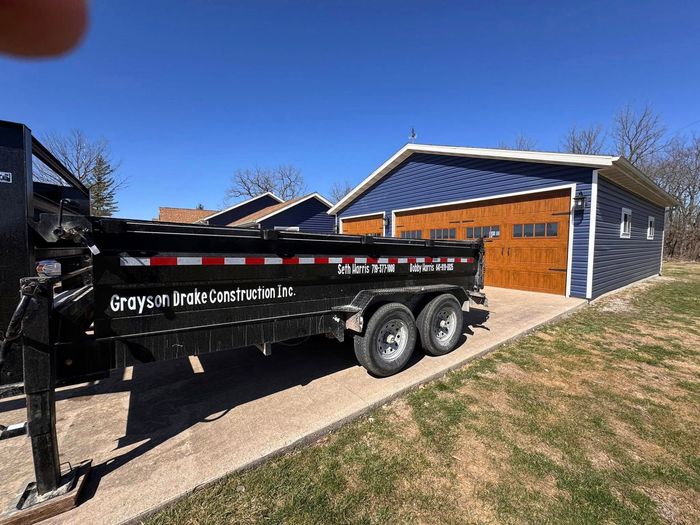 A dump truck is parked in front of a garage. A dump truck is parked in front of a garage.