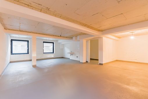 An empty room with white walls and a sink in it.