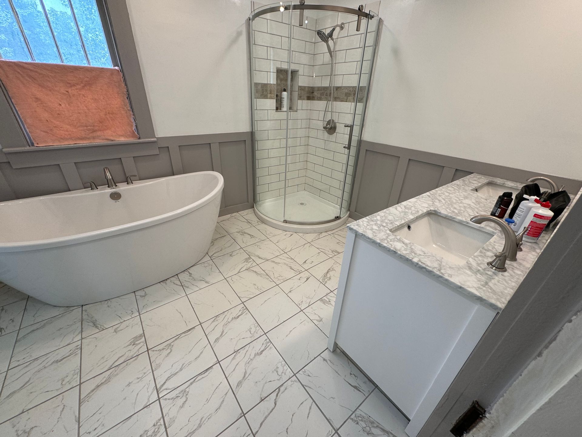 A bathroom with blue cabinets , two sinks , two mirrors and a tub.