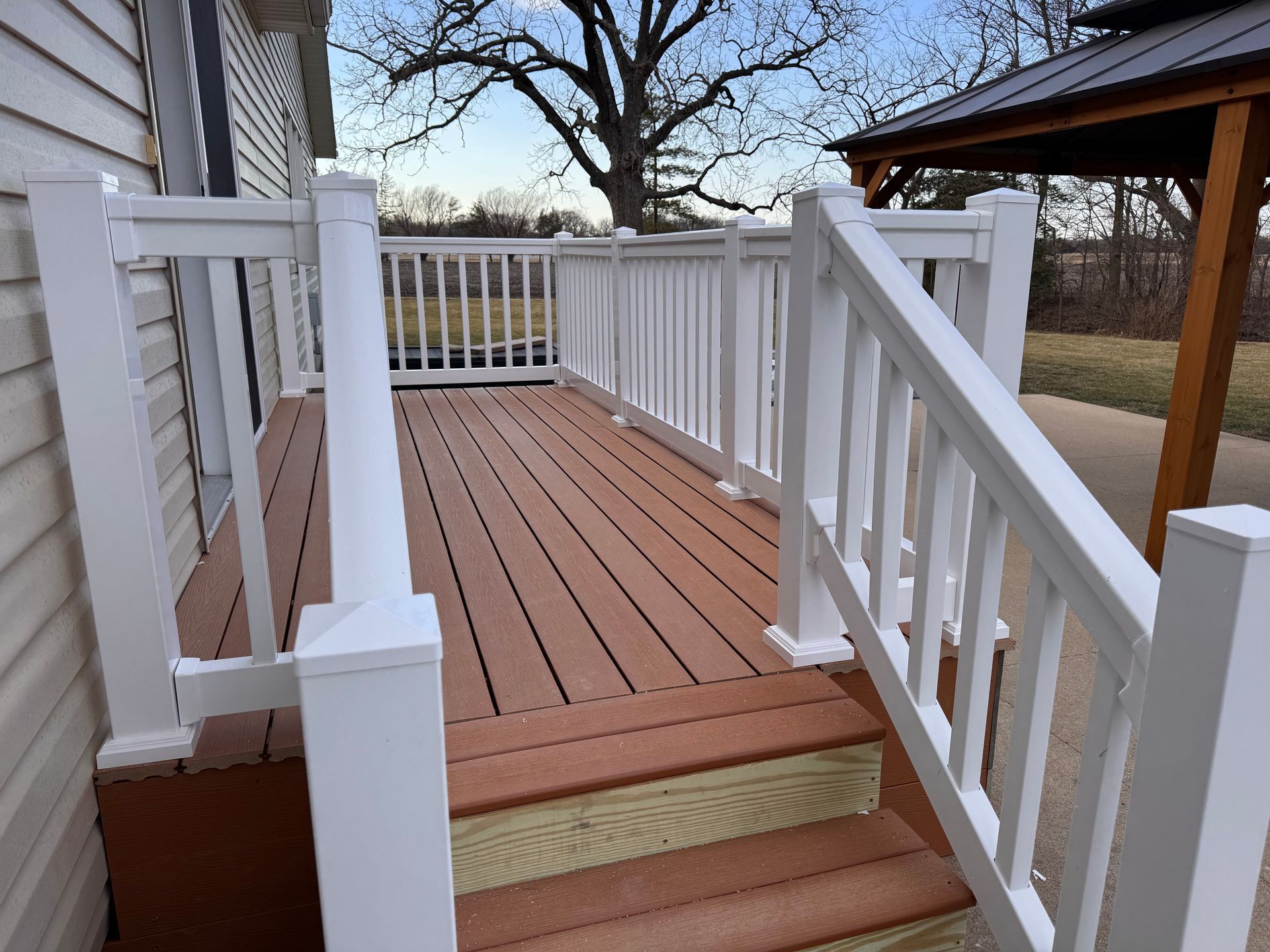 A large wooden deck with sliding glass doors and a wooden railing.