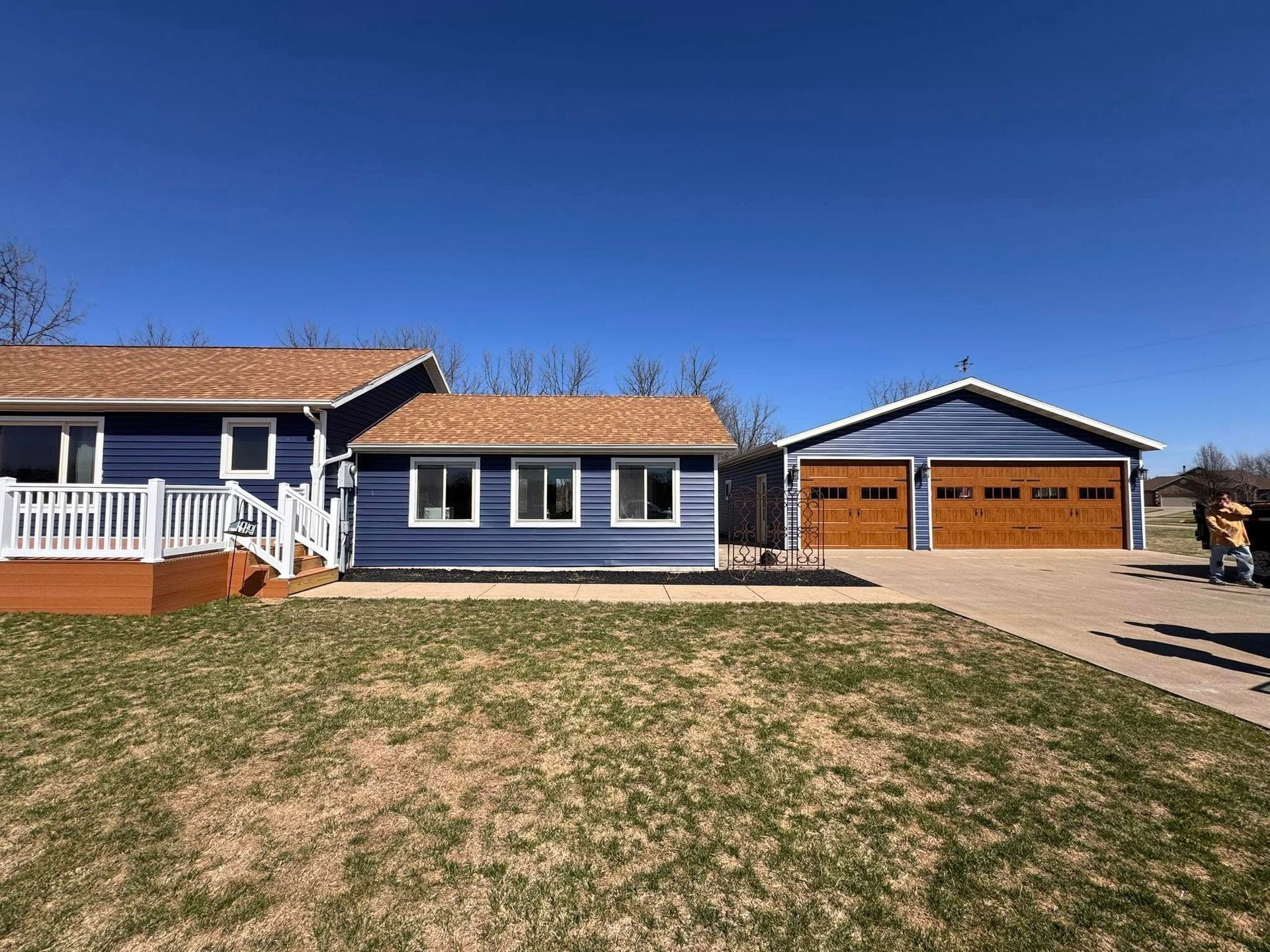 A blue house with a brown roof and two garage doors.